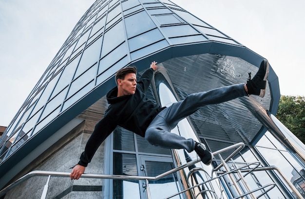 Giovane che fa parkour in città durante il giorno. Concezione degli sport estremi.