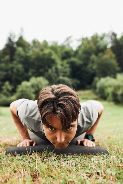 Giovane che fa push-up fuori sull'erba durante il suo allenamento di calistenia