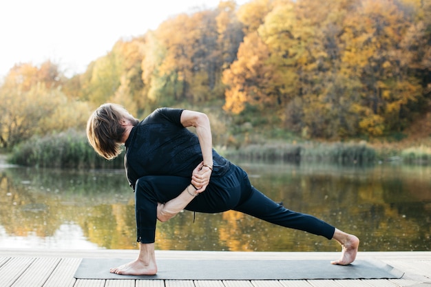 Giovane che fa yoga asana in natura vicino al lago