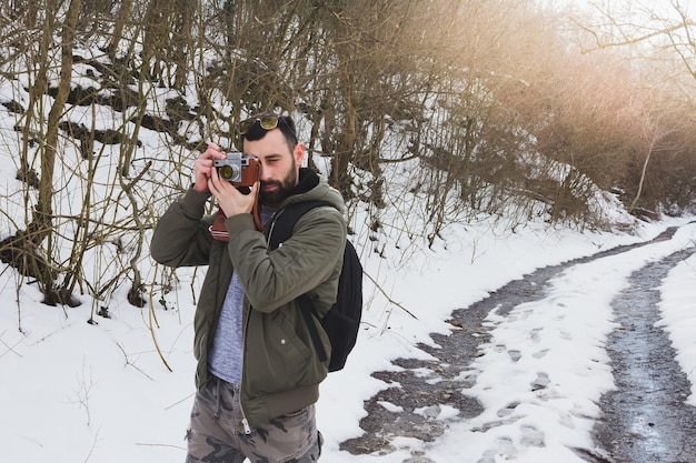 Giovane che fotografa in piedi sulla strada coperta di neve