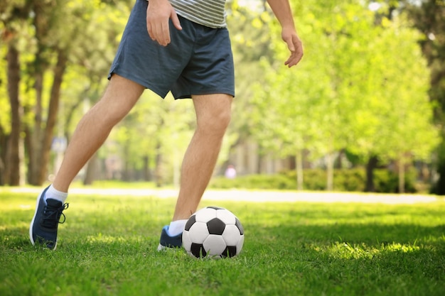 Giovane che gioca a calcio sull'erba verde nel parco