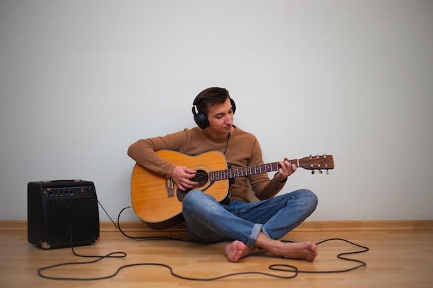 Giovane che gioca su una chitarra con la parete sullo sfondo