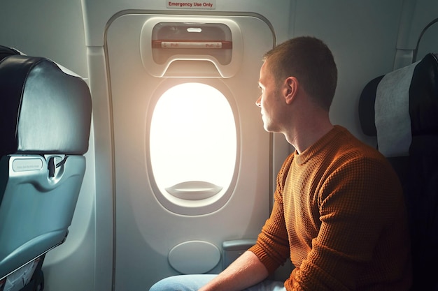 Giovane che guarda attraverso la finestra mentre viaggia in aereo