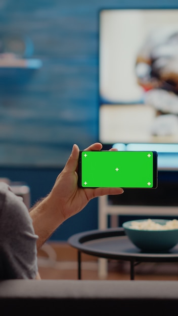 Giovane che guarda lo schermo verde orizzontale sullo smartphone