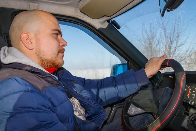 Giovane che guida un'auto sulla strada d'inverno. Vista interna