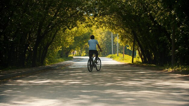 Giovane che guida una bicicletta nel parco verde