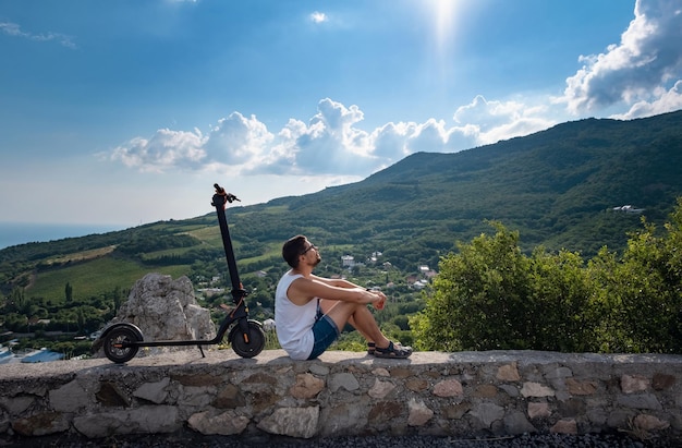 Giovane che guida uno scooter elettrico sulla catena montuosa Concetto di trasporto ecologico