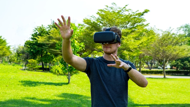 Giovane che indossa occhiali per realtà virtuale e gesticolano nel parco