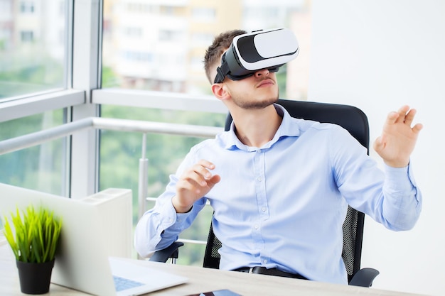 Giovane che indossa occhiali per realtà virtuale in un ufficio moderno.