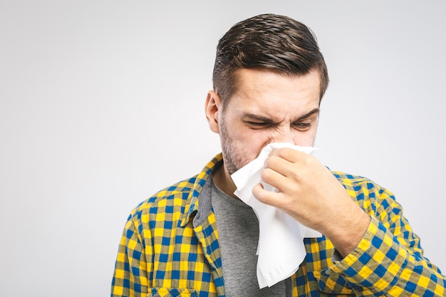 Giovane che indossa una camicia casual che soffia il naso