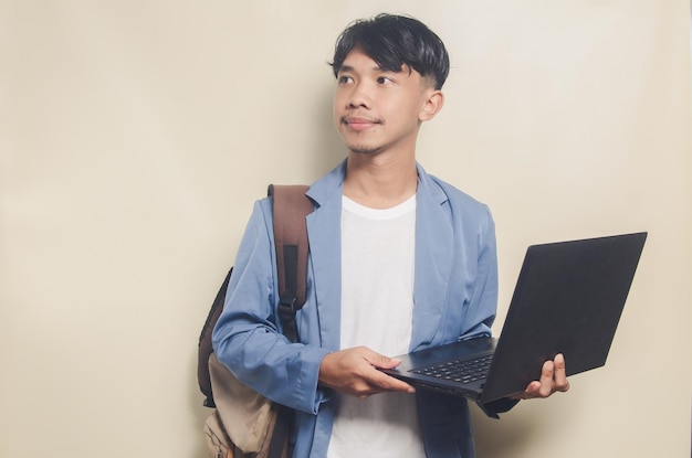 Giovane che indossa una tuta da college mentre si trasporta il laptop su sfondo isolato