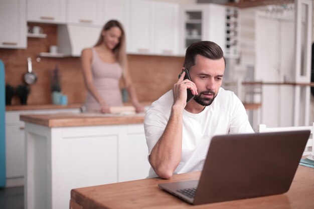 Giovane che lavora al computer portatile nella cucina di casa