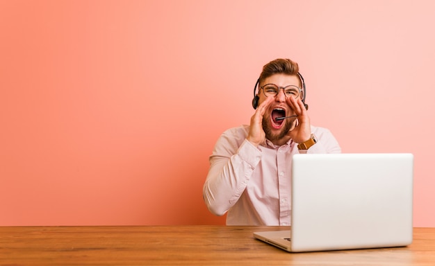 Giovane che lavora in un call center che grida eccitato alla parte anteriore.