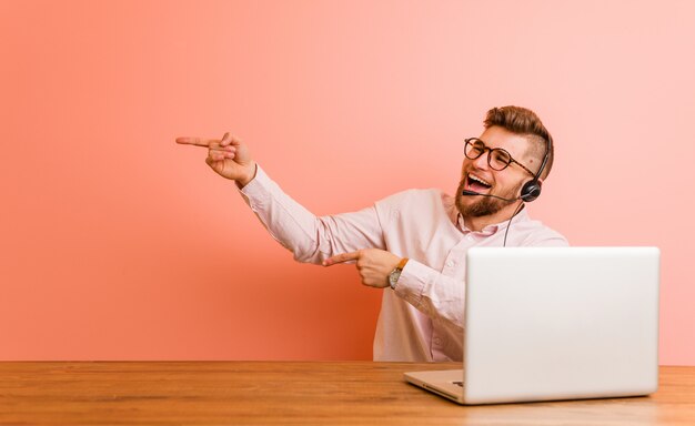 Giovane che lavora in un call center eccitato indicando con gli indici di distanza.