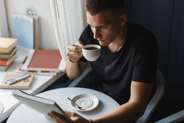 Giovane che legge un libro e beve caffè in un ristorante