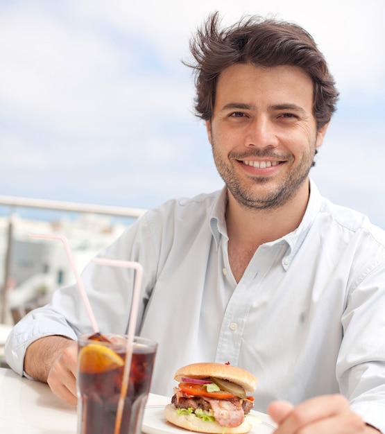 Giovane che mangia un hamburguer