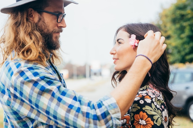 Giovane che mette fiore tra i capelli della sua ragazza guardando negli occhi