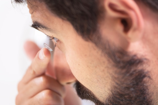 Giovane che mette lenti a contatto nel suo occhio sinistro, da vicino