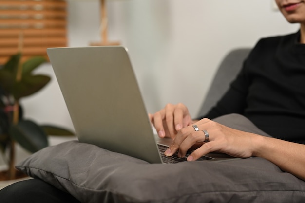 Giovane che naviga in internet con il computer portatile sul divano.