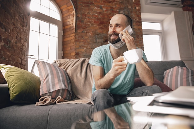 Giovane che parla al telefono a casa mentre è in quarantena e lavora come freelance