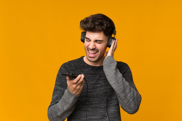 Giovane che per mezzo del cellulare con le cuffie e cantare