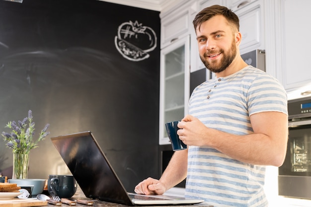 Giovane che per mezzo del computer portatile alla prima colazione