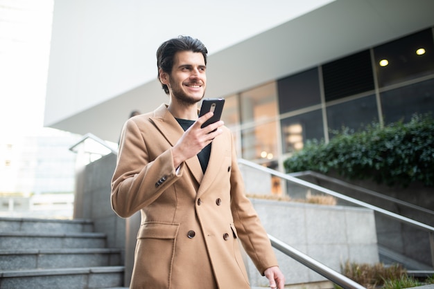 Giovane che per mezzo del suo cellulare all'aperto