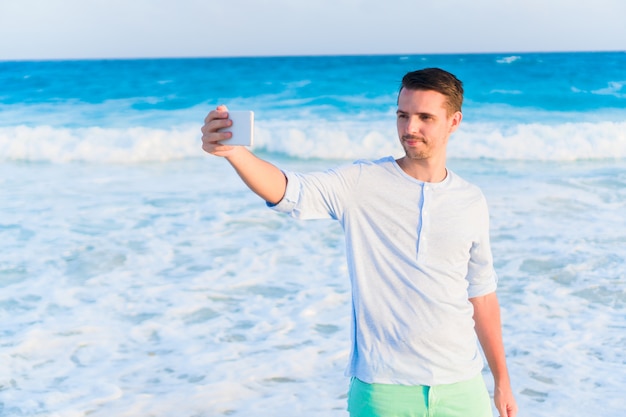 Giovane che prende selfie sulla spiaggia sulla vacanza caraibica