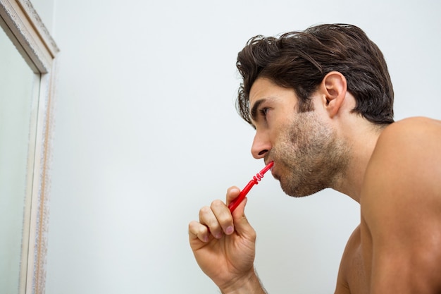 Giovane che pulisce i suoi denti in bagno