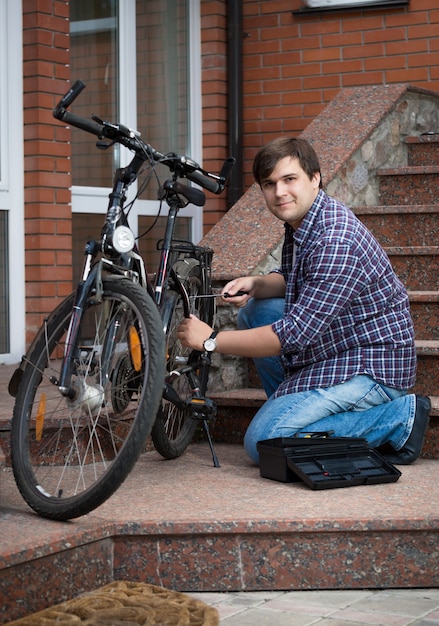 Giovane che ripara la bicicletta sul portico di casa sua