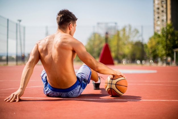 Giovane che riposa giocando a basket