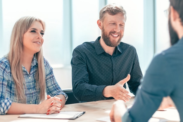 Giovane che risponde alle domande dei manager durante un colloquio. il concetto di occupazione