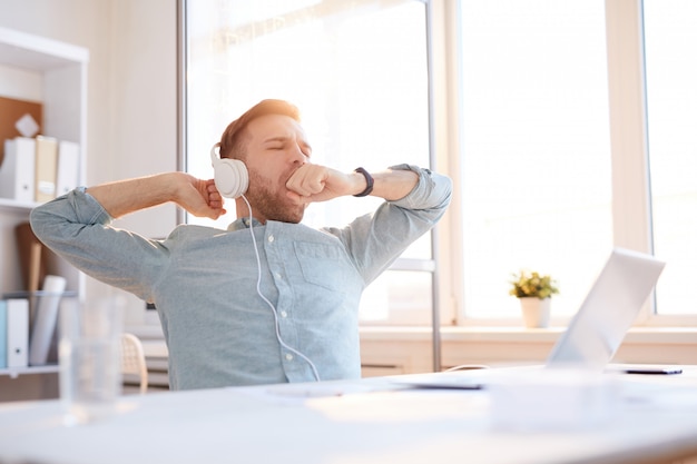 Giovane che sbadiglia sul posto di lavoro