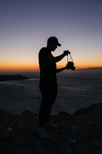 Giovane che scatta foto in cima a una montagna al tramonto