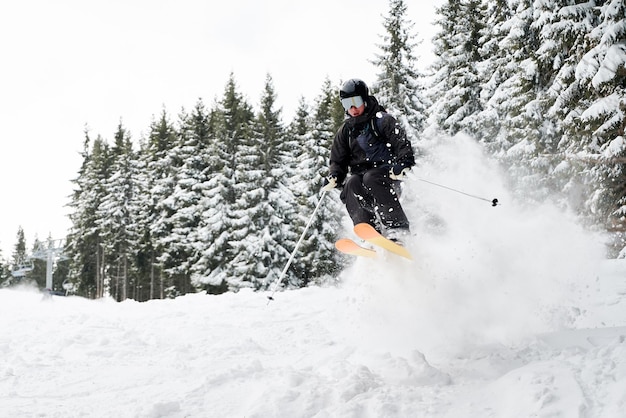 Giovane che scia in discesa attraverso la neve farinosa profonda