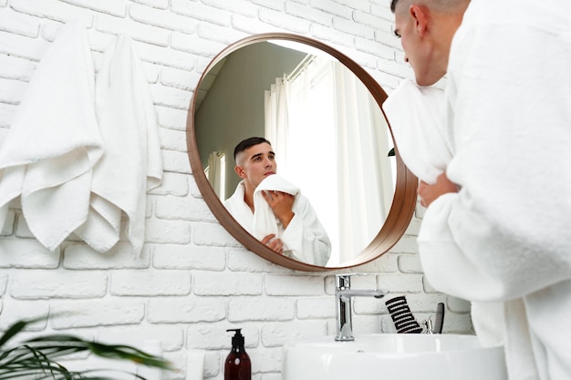 Giovane che si guarda nello specchio in bagno