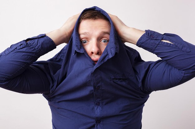 Giovane che si nasconde in una camicia blu che lavora a maglia le sopracciglia con rabbia
