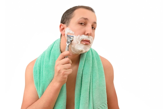 Giovane che si rade con un rasoio su uno sfondo bianco isolato cura del corpo e concetto di igiene maschile