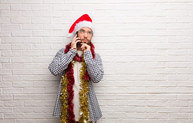 Giovane che si siede con i regali che celebrano il natale che pensa ad un&#39;idea