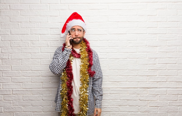 Giovane che si siede con i regali che celebrano il natale che pensa ad un&#39;idea