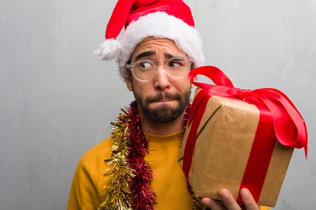 Giovane che si siede con i regali che celebrano il natale che pensa ad un&#39;idea