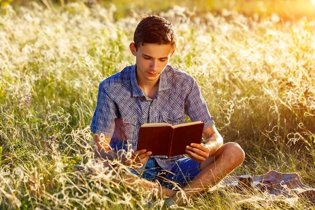 Giovane che si siede in natura che legge un libro