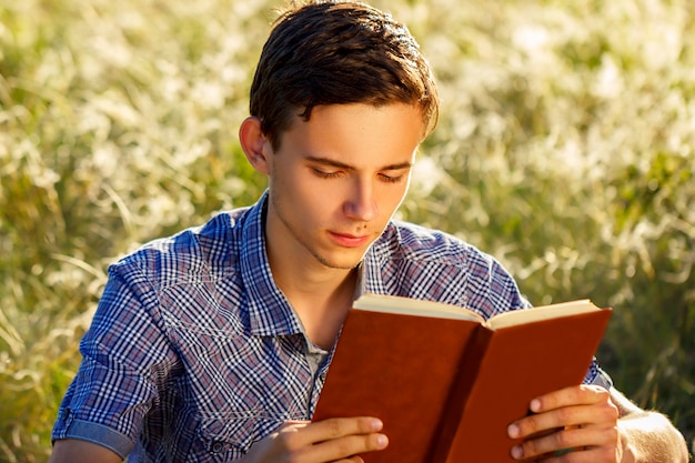 Giovane che si siede in natura che legge un libro