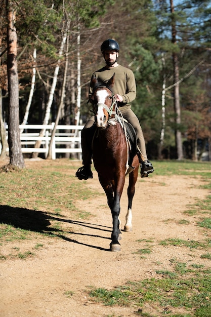 Giovane che si siede su un cavallo all'aperto