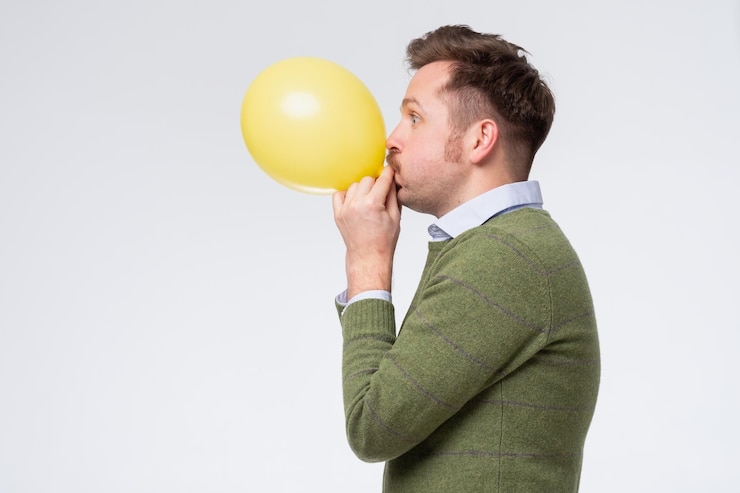 Foto giovane che soffia un palloncino giallo allenando i suoi polmoni dopo il coronavirus