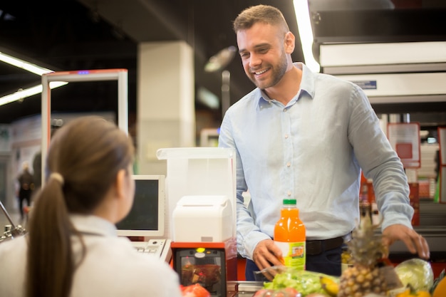 Giovane che sorride al cassiere in supermercato