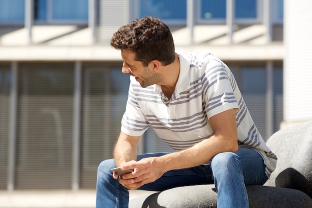 Giovane che sorride con il cellulare all&#39;aperto