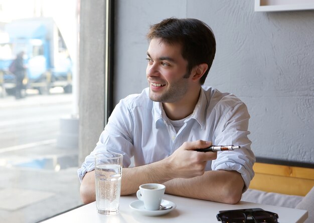 Giovane che sorride con la sigaretta elettrica all&#39;interno