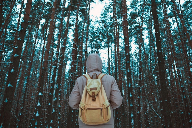 Giovane che sta nella foresta nevosa di inverno