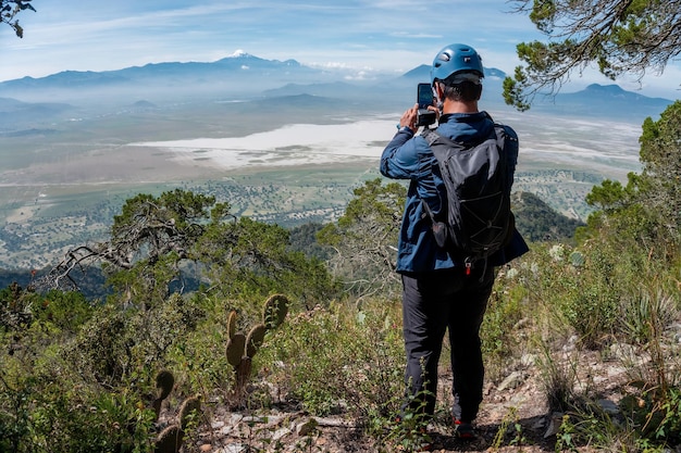 Giovane che sta sulle montagne superiori che gode della vista della natura